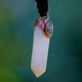 Hand Holding Labradorite and White Quartz Crystal Pendant in Sunlight to Reveal Colors